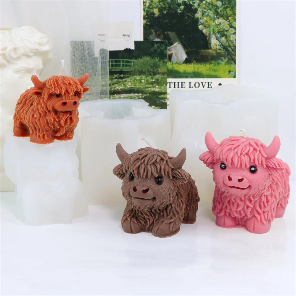 Three silicone molds of Highland cows in orange, brown, and pink colors displayed on white candles.