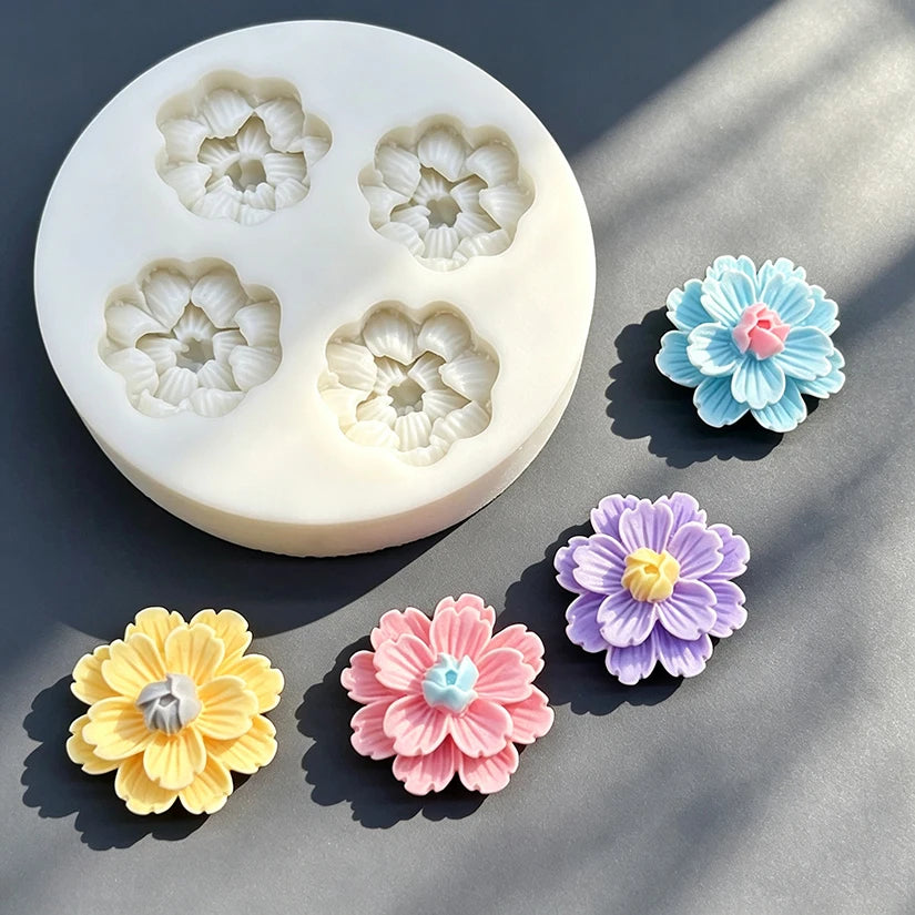 A silicone mold with five daisy flower shapes in various shades of blue, purple, and pink for cake decorating.