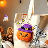 A beige tote bag features a Halloween plush keychain set including a ghost, pumpkin, and bat charm.