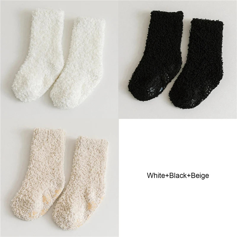 Three pairs of baby anti-slip fleece socks in white, black, and beige.