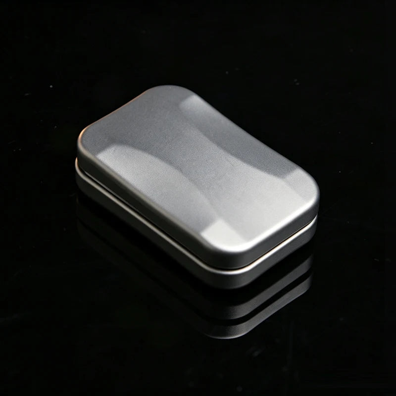 A silver metal fidget slider with a smooth, oval shape is shown on a reflective black surface.