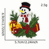 A white snowman patch with a black hat and scarf, surrounded by green foliage and a red gift box.