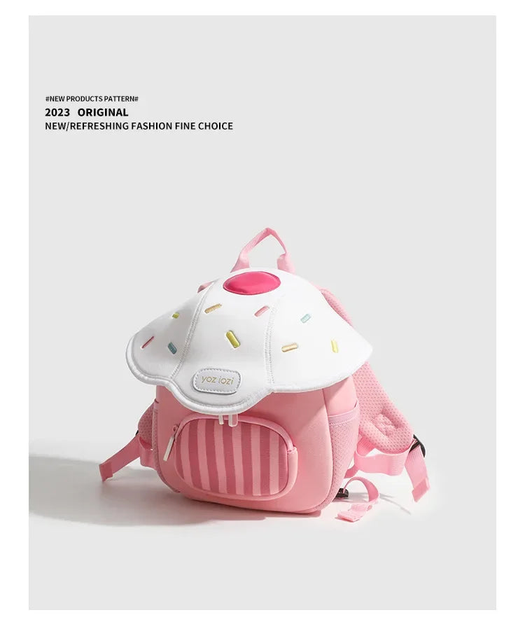 A pink mini backpack with a white mushroom design and pink straps is shown against a light gray background.