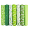 A pack of seven vertical rolls of green fabric with white and multi-colored floral patterns for quilting