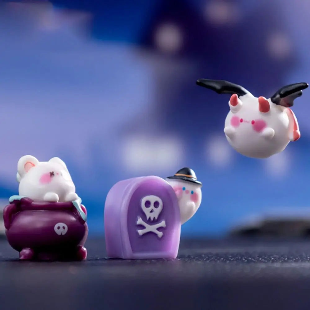 Three small ceramic figurines of cartoon animals, including a pink bear and a purple skull-faced figure, are displayed agains