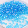 A pile of small, translucent blue glass rice beads for DIY jewelry and crafting.