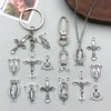 A collection of vintage antique silver cross charms and pendants for jewelry making displayed on a gray surface.