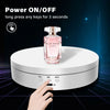 A hand presses a button on a white display stand which holds an Elie Saab perfume bottle.