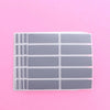 A sheet of clear scratch-off sticker film divided into multiple rectangular sections on a pink background.