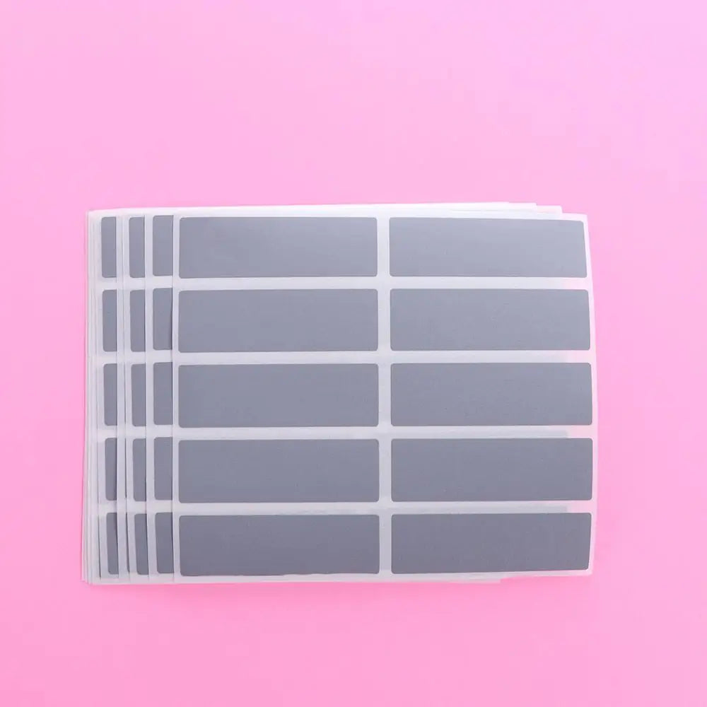 A sheet of clear scratch-off sticker film divided into multiple rectangular sections on a pink background.