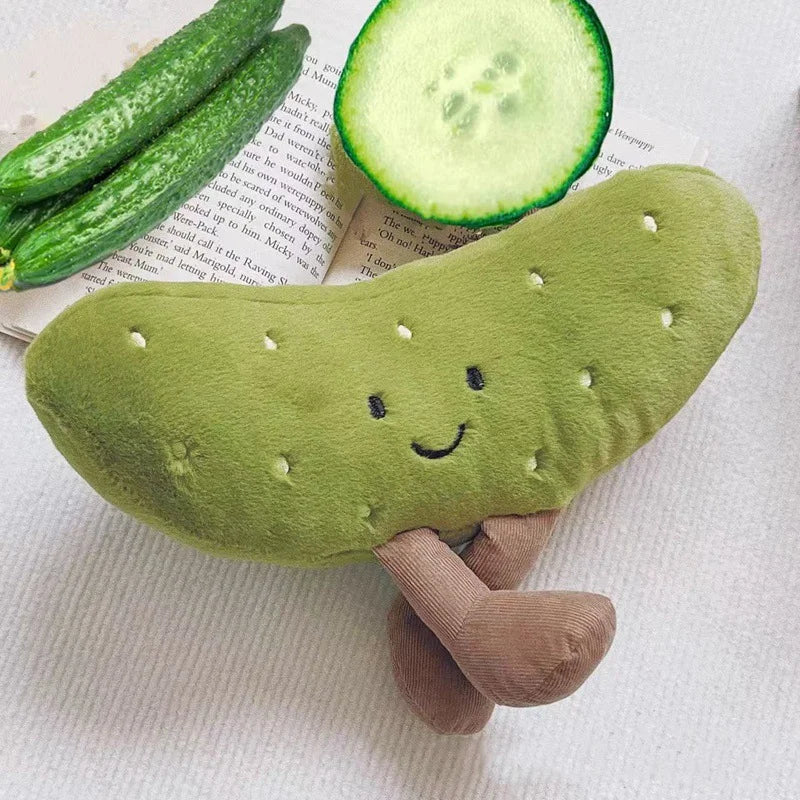 A soft green plush pickle toy with a smiling face is resting on a piece of paper.