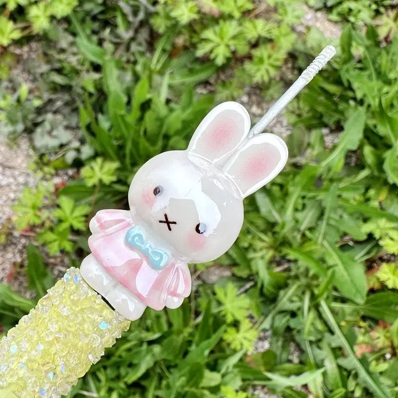 A small white Miffy resin bead charm with pink accents is attached to a yellow textured string.