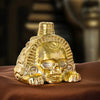 A handcrafted golden Aztec death whistle featuring a skull design resting on brown fabric.