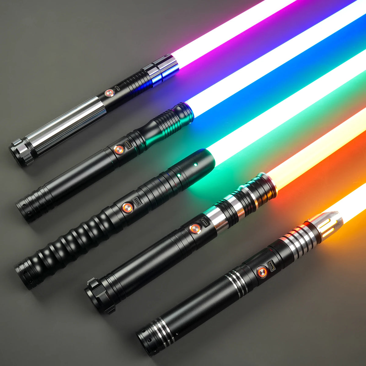 A set of three heavy dueling lightsabers with glowing neon blue, white, and orange blades displayed on a dark surface.