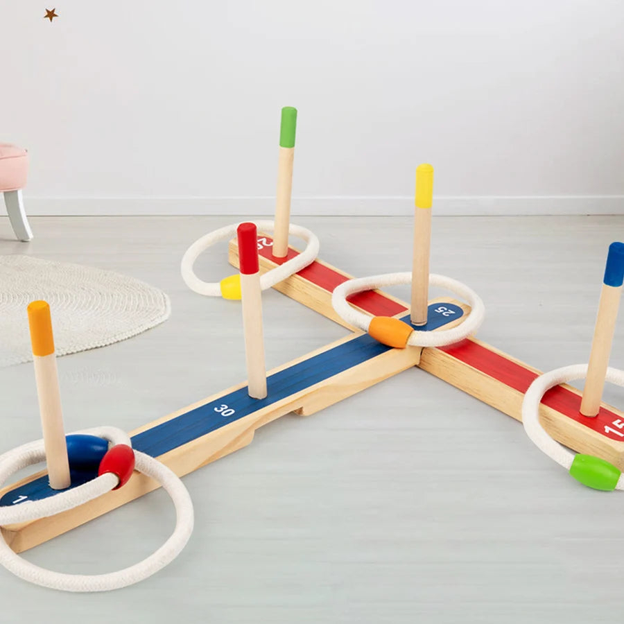 A wooden ring toss game for kids featuring colored wooden pegs and rings on a light gray floor.