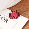 A set of dragon dice enamel pins featuring red and black designs resting on a brown burlap fabric.