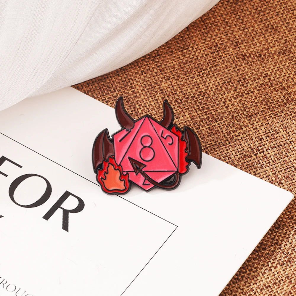 A set of dragon dice enamel pins featuring red and black designs resting on a brown burlap fabric.