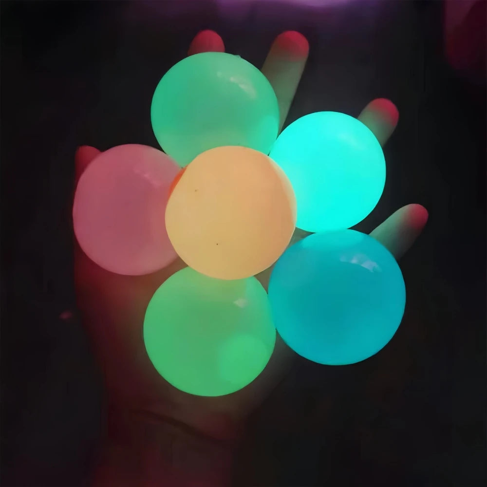 A hand holds several glowing, translucent stress balls in various shades of green, yellow, and blue.