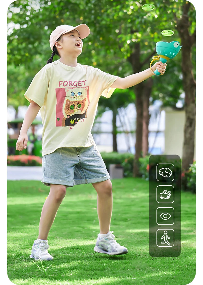 A young girl is playing with a green pull-string flying saucer launcher toy outdoors on the grass.