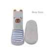 A grey bear shaped non-slip sock for babies and toddlers with blue stripes and a matching sole.