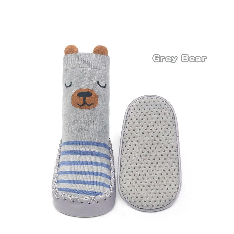 A grey bear shaped non-slip sock for babies and toddlers with blue stripes and a matching sole.