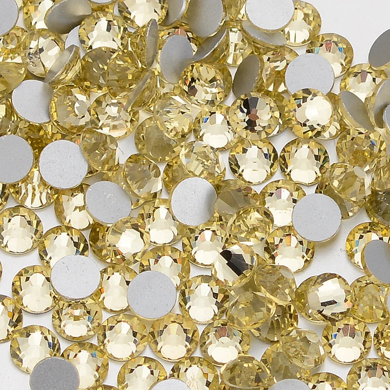 A close-up view of small, round, faceted yellow glass crystal flatback rhinestones.