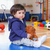 A baby doll with soft cloth body wearing a blue hoodie sitting on a blue surface.