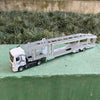 A silver diecast model of a 1:50 scale container truck with lights and sounds on a green surface.