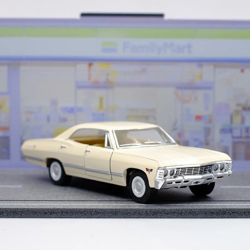 A diecast model of a 1967 Chevrolet Impala in cream color displayed on a gray surface.