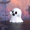 A white ghost-shaped figurine with black eyes and mouth, shown against a blurred background.