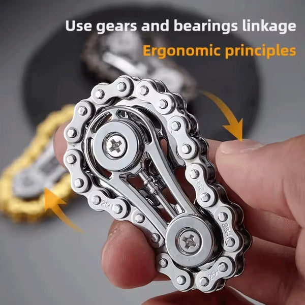 A hand holds a silver metal fidget spinner with gears and bearings linkage, demonstrating ergonomic principles.
