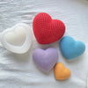 A collection of silicone heart molds in red, white, blue, purple, and orange resting on a white cloth.