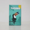 A box for a Tucano board game featuring a stylized toucan bird and green tropical leaves.