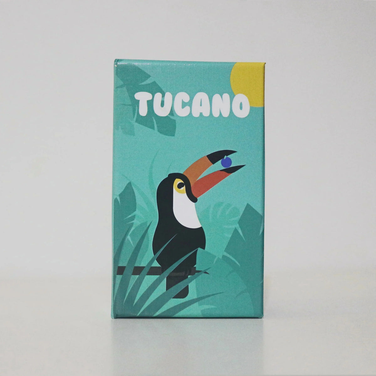 A box for a Tucano board game featuring a stylized toucan bird and green tropical leaves.