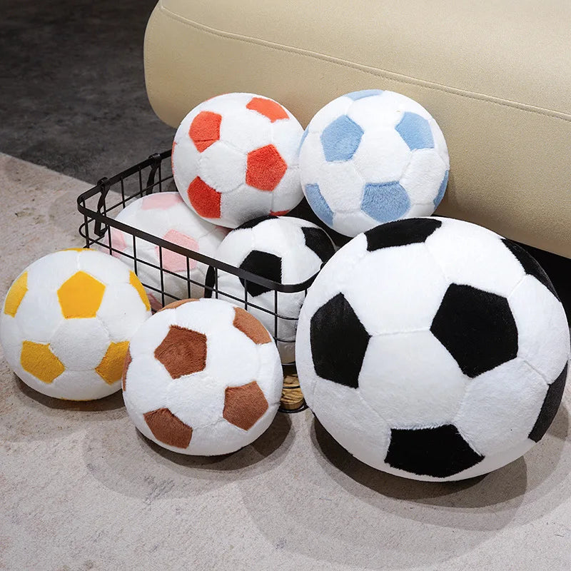 A collection of realistic football plush pillows in various colors including white, orange, blue, and black resting on a ligh