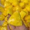 A hand holds a yellow, triangular squeeze toy shaped like a cheese ball stress relief item.