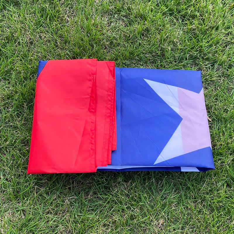 A folded red and blue Puerto Rico national flag banner lying on green grass.