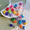 A white oval dish holds various colorful acrylic letter beads for jewelry and crafting.