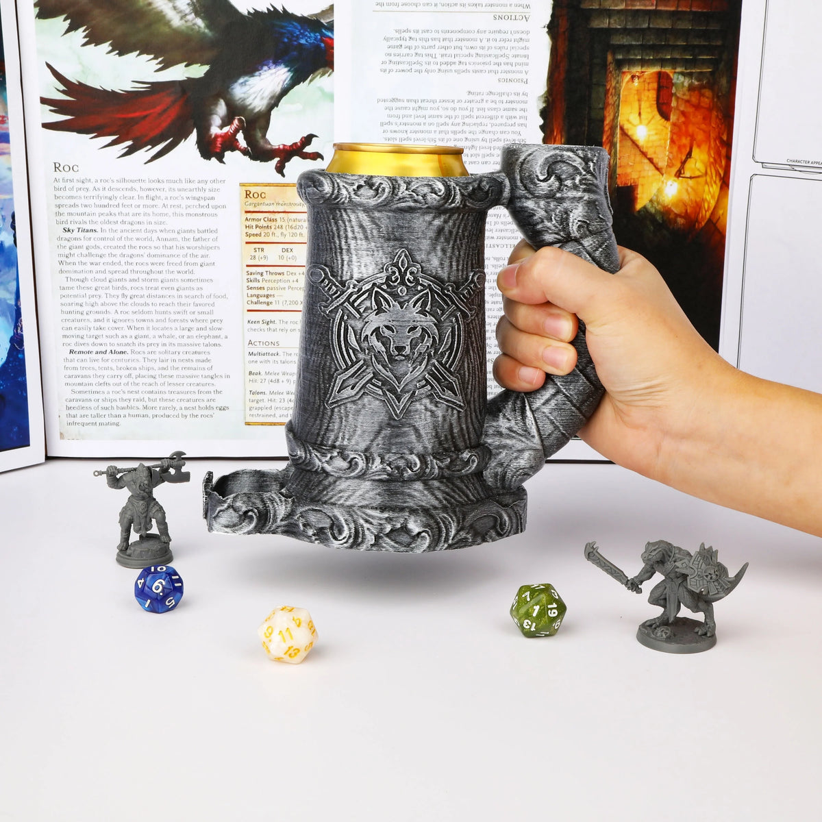 A hand holds a dark gray metal dice tower mug featuring a wolf emblem, with several dice and a small figurine nearby.