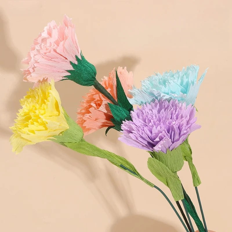 Ein Strauß handgemachter Crêpepapierblumen in Rosa-, Gelb-, Orange- und Blautönen auf hellem Hintergrund.