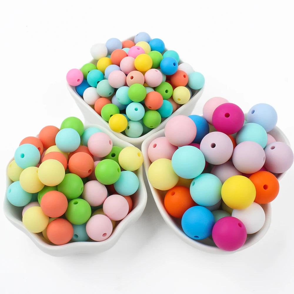 A bowl filled with a colorful mix of round silicone beads in various shades of pink, blue, yellow, and green.