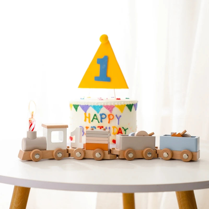 A wooden train set with numbered cars, including a cake topper shaped like the number one.