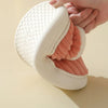 A hand is holding a white faux fur slipper with a pink interior lining.
