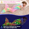 A child wearing a glow-in-the-dark mermaid tail blanket in bright light and a dark room.