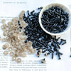 A bowl filled with small black plastic safety eyes for crafting, alongside loose eyes.