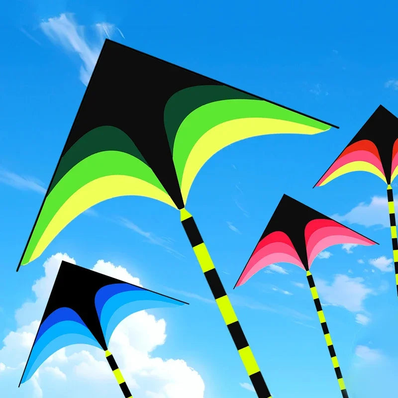 A collection of colorful delta kites with black and neon accents flying against a bright blue sky.