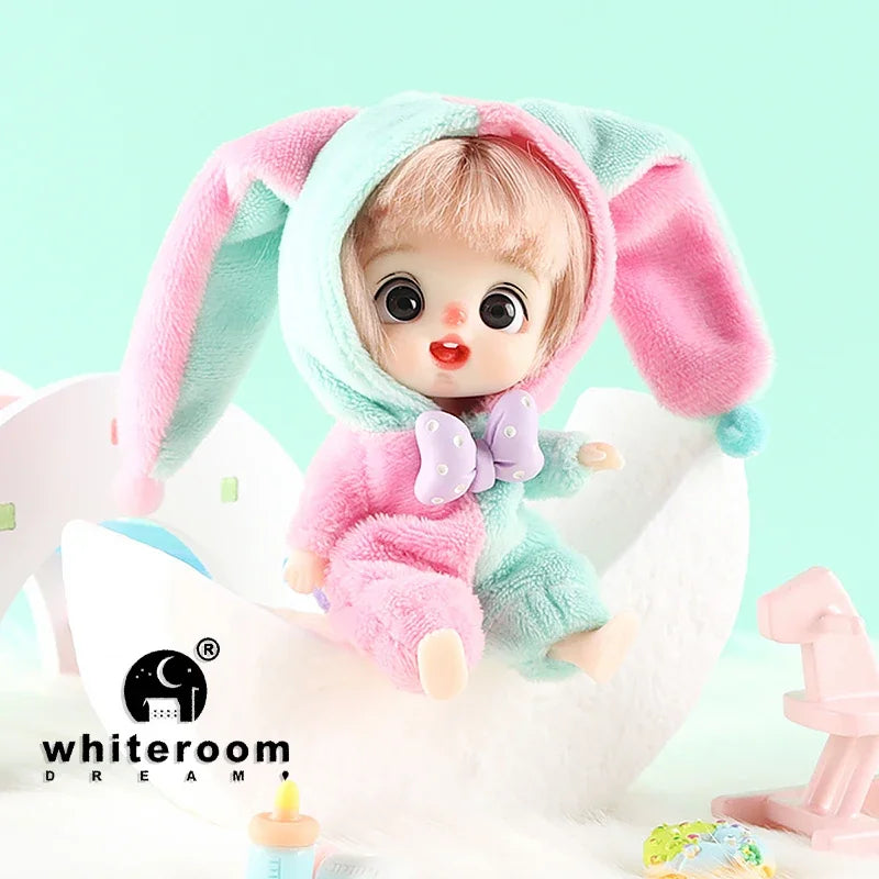 A small, pink and teal plush doll with long ears is shown against a white background.