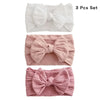 A set of three soft stretch baby headbands with bows in white and pink shades.