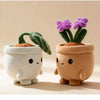 A pair of cute plush toys resembling potted succulents with green leaves and purple flowers in terracotta pots.