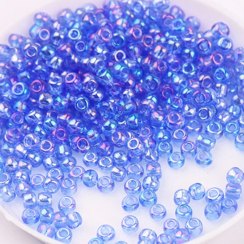 A pile of small, iridescent blue and purple glass rice beads for DIY jewelry and crafting.